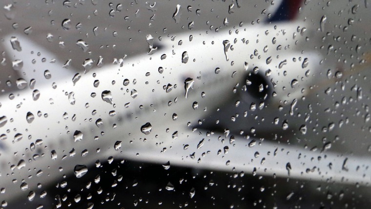 A plane sits on the tarmac behind rain drops on a window