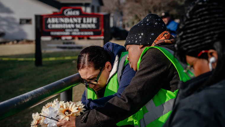 People bring flowers to a makeshift memorial at Abundant Life Christian School