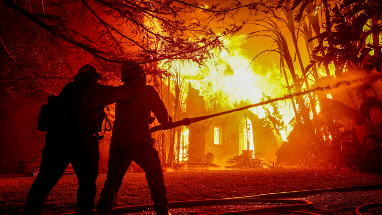 Firefighters spray water on a burning home.