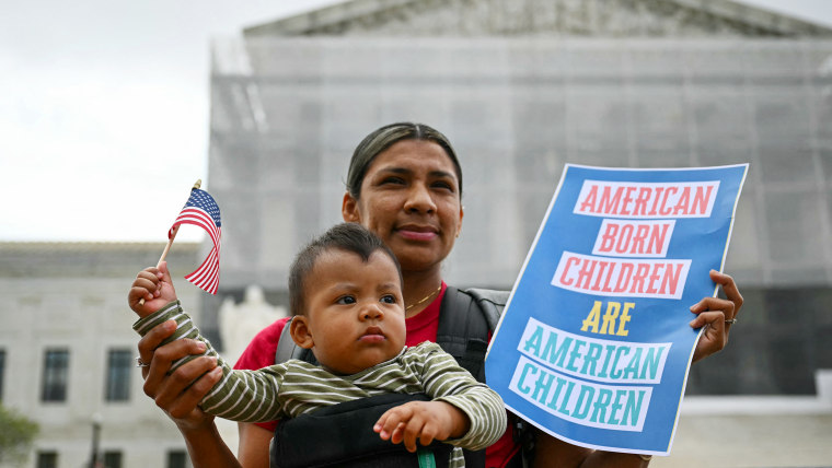 Olga Urbina holds a sign that reads "American Born Children are American Children" as her son Aers holds an American flag.