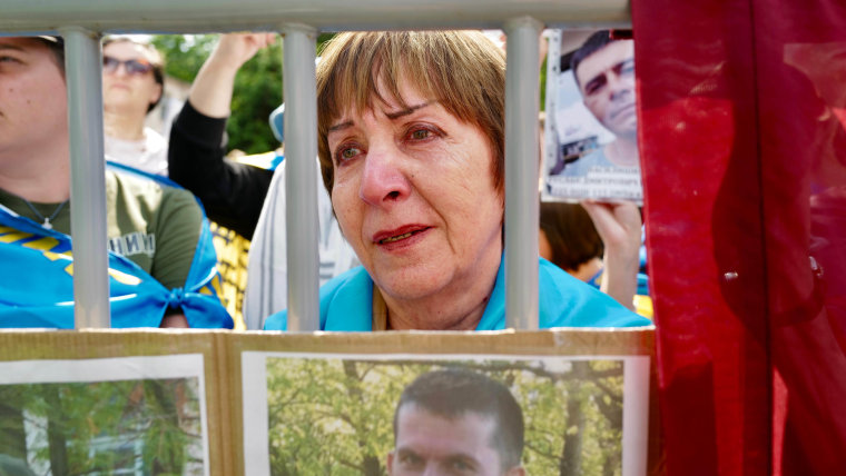 A tearful woman standing behind a barrier