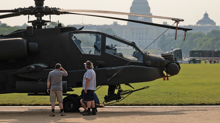 People pause to look at a U.S. Army AH-64 Apache attack helicopter parked on display on the National Mall on June 11, 2025.
