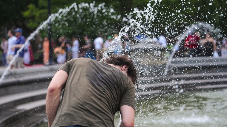 A person places their head under water streams at a fountain