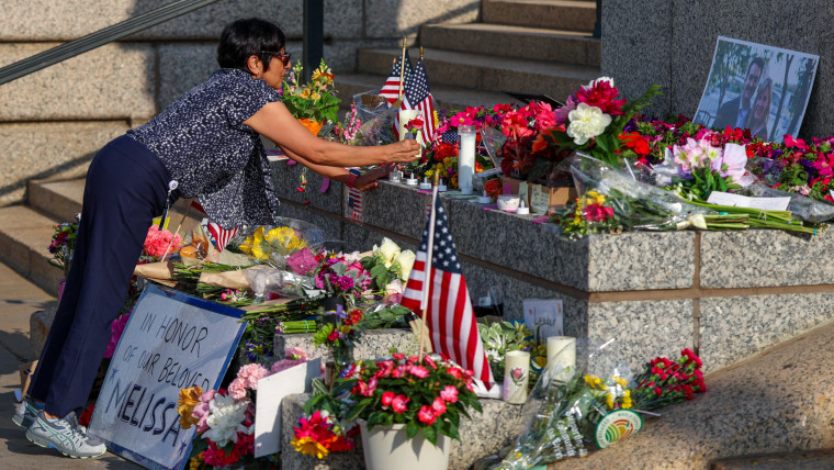 A woman lays flowers at a makeshift memorial.