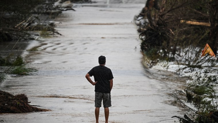 A man looks at a damaged road after severe flash flooding