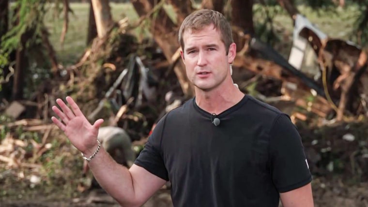 Morgan Chesky speaks outside in the forest near flood debris