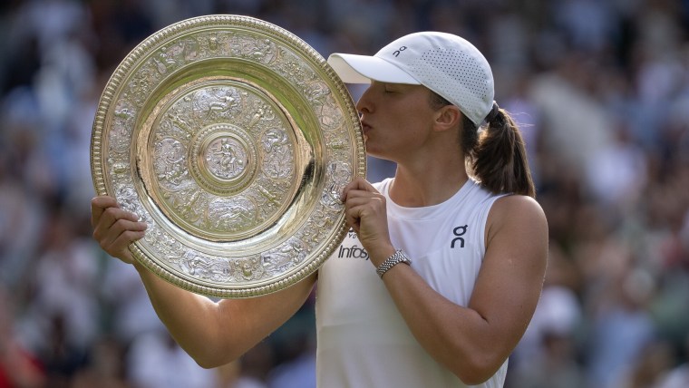 Jul 12, 2025; Wimbledon, United Kingdom; Iga Swiatek of Poland kisses the trophy after winning the women’s final match against Amanda Anisimova of the United States on day 13 at All England Lawn Tennis and Croquet Club. Mandatory Credit: Susan Mullane-Imagn Images