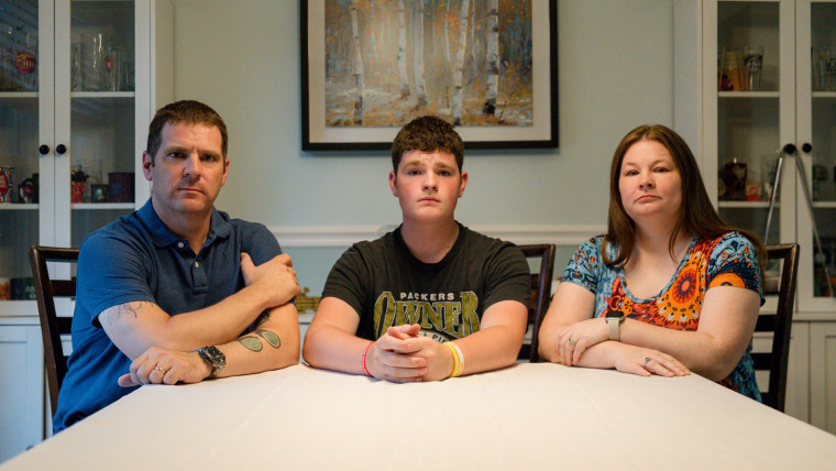 From left, Nick, Jonathan, and Misty Benz-Bushling sit at their kitchen table to pose for a photo