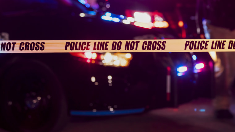 Two police officers behind crime scene tape