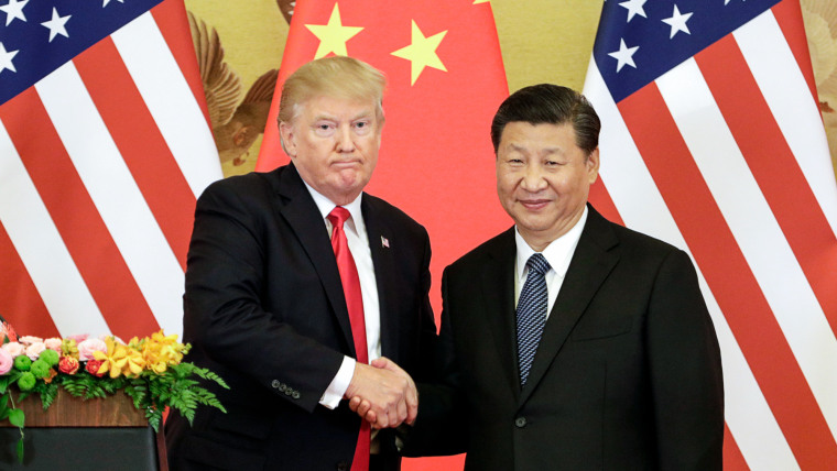 Donald Trump, left, and Xi Jiping shake hands while standing in front of American and Chinese flags