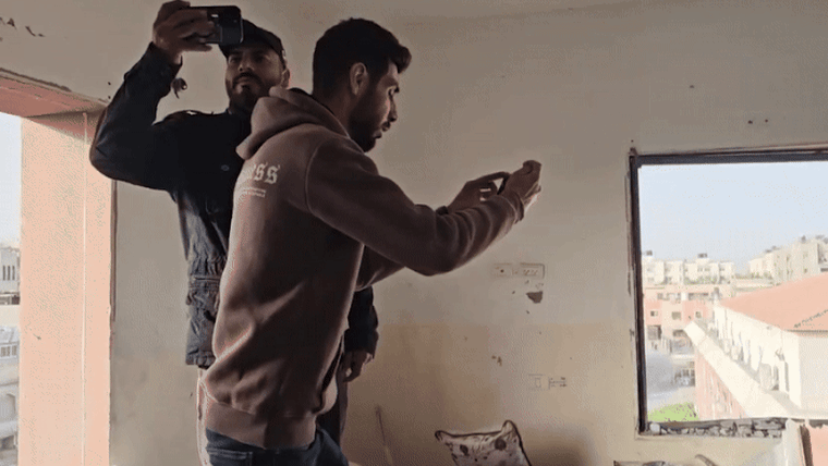 Samir and Samed film with their phones inside a building full of rubble in Gaza.