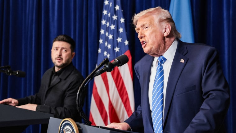 Volodymyr Zelenskyy, left, stands on a podium on stage next to Dondald Trump, who speaks at a podium beside him