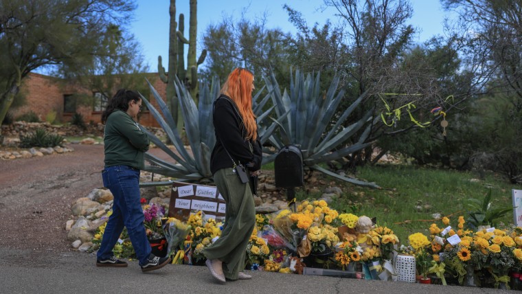 People visit a memorial set up near the driveway to Nancy Guthrie's residence in Tucson, Arizona.