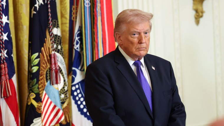 President Trump standing next to multiple flags.