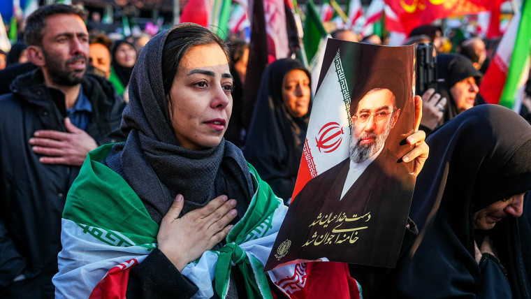 Image: A woman holds a picture of Iran's new Supreme Leader Ayatollah Mojtaba Khamenei