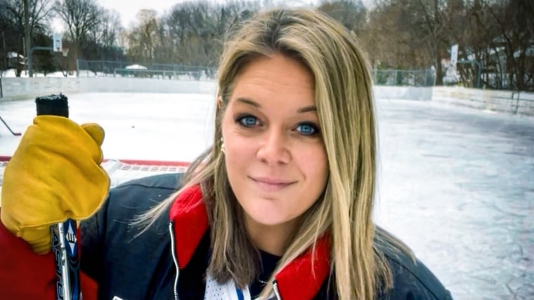 Jessi Pierce stands outside holding a hockey stick on an ice rink
