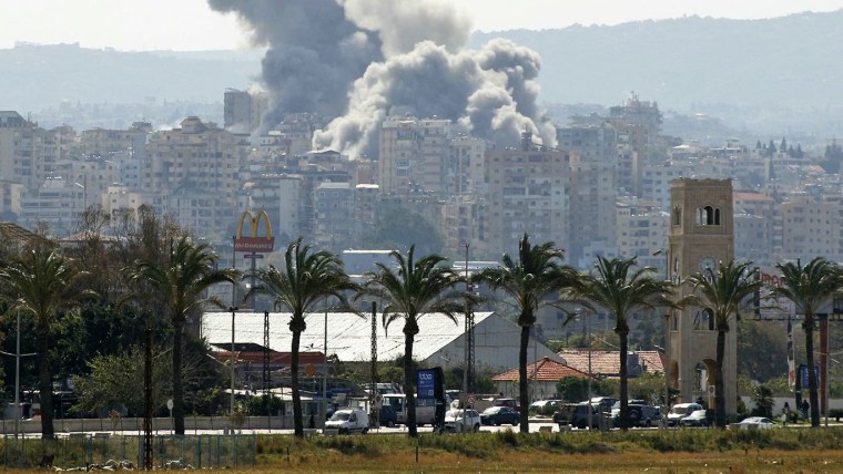 Smoke rises behind palm trees and a McDonald's "Golden Arches" sign in Al-Hosh, Lebanon, a suburb of Tyre on April 14, 2026.