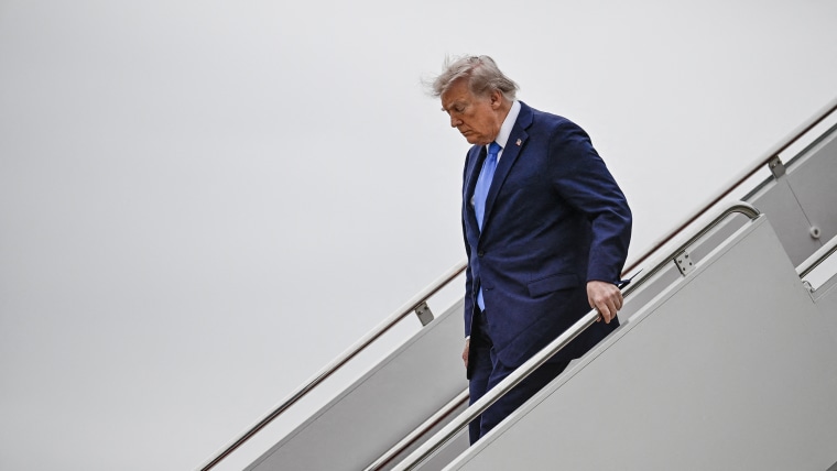 Donald Trump descending the stairs from Air Force One against a gray background.