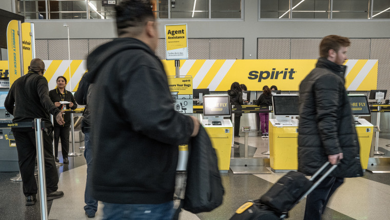 People walk by Spirit Airlines counters inside an airport.