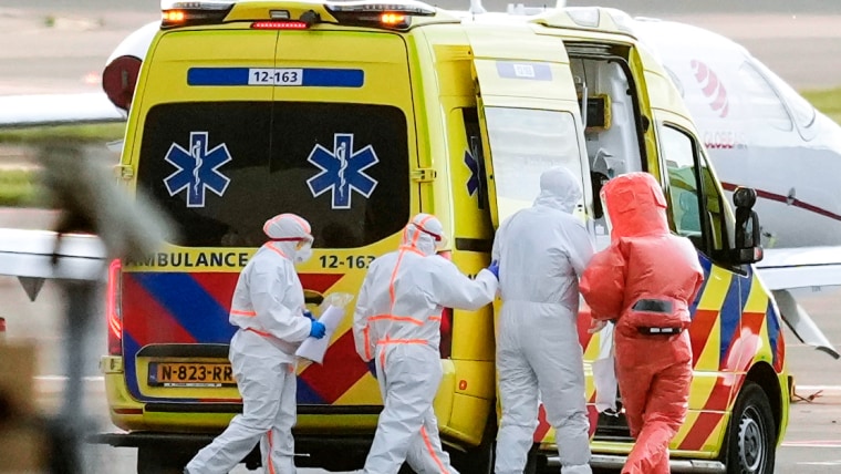 Medics escort a patient, second right, to an ambulance