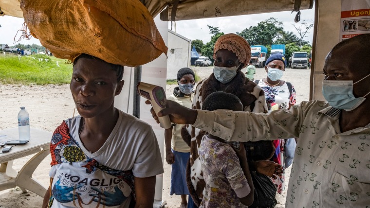 A border health officer at the Busunga crossing between Uganda and the Democratic Republic of Congo checks a traveler's temperature.