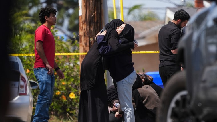 People embrace near the scene of a shooting outside the Islamic Center of San Diego