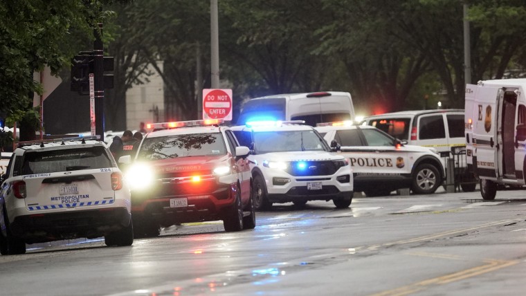 Several police patrol vehicles with lights flashing on a wet city street.