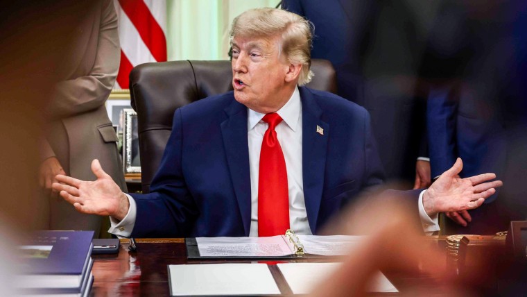 Donald Trump speaks while seated at a desk in the oval office