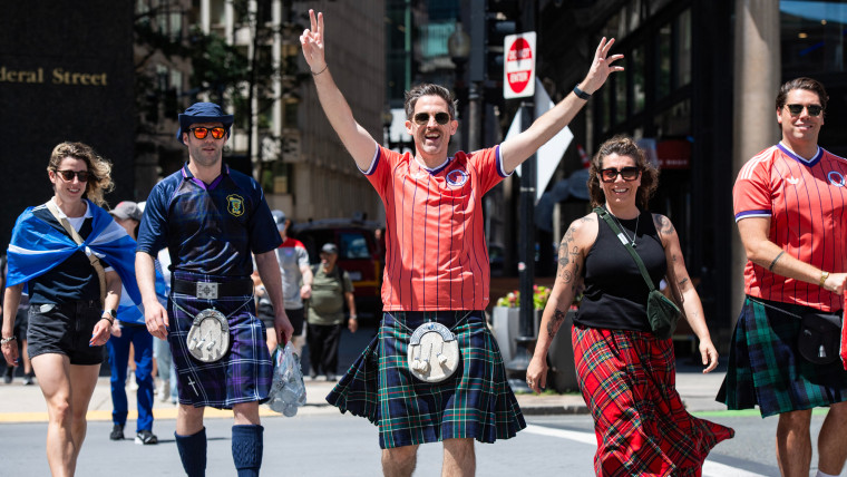 People wearing tartans walk down a street outside