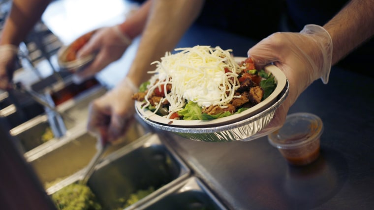 An employee prepares a burrito bowl at a restaurant.