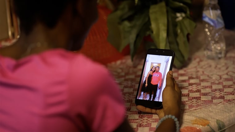 Image: Maggie looking at her phone with a photo of her and her father.