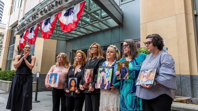 Parents hold pictures of their children.