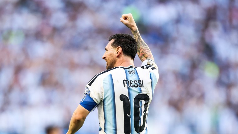 Lionel Messi pumps a fist in the air while walking on the field, wearing an Argentina jersey