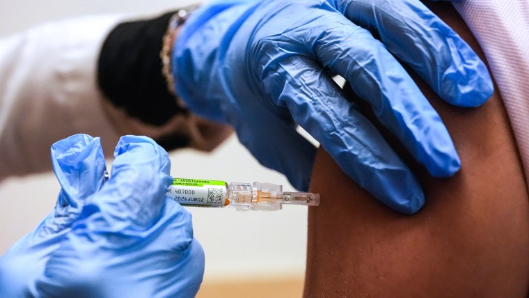 Gloved hands administer a flu shot to someone's arm