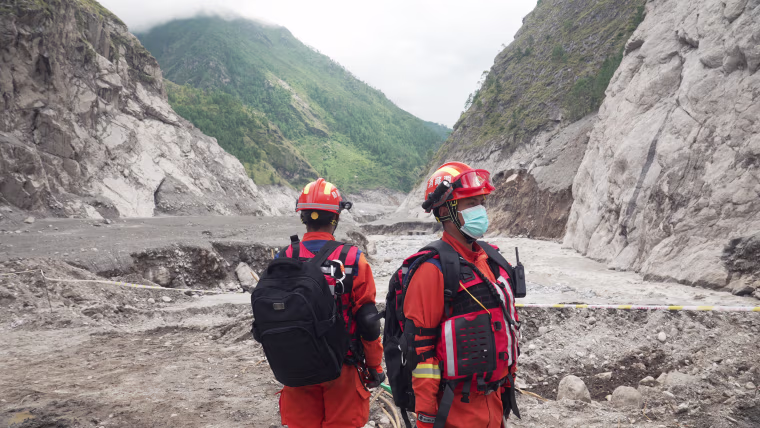 Image: Two rescuers in orange emergency services uniform.