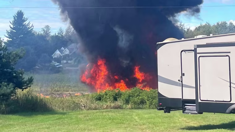 Smoke rises behind a motorhome.