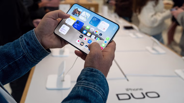 A person holds an Apple iPhone Duo smartphone.