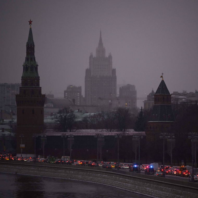 Cars slowly move along an embankment of the Moskva river past the Kremlin