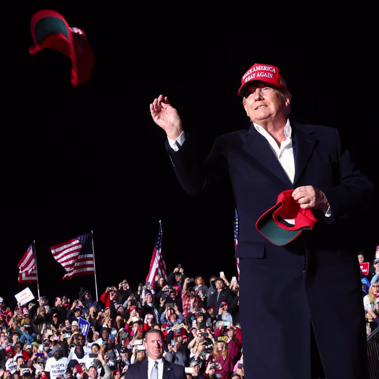 President Donald Trump tosses a MAGA hat.