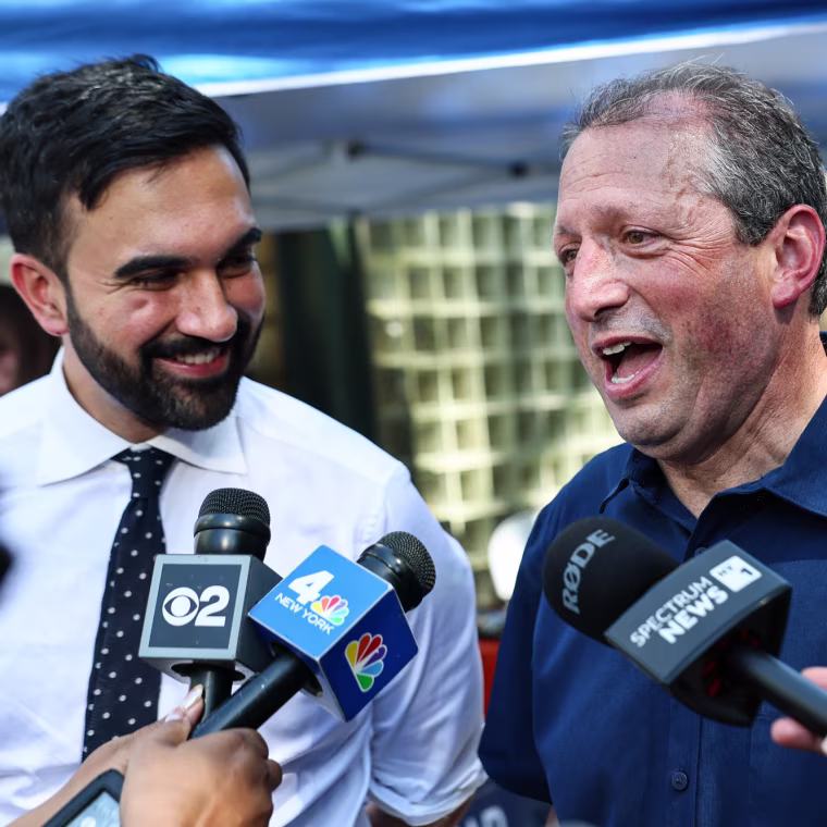 Zohran Mamdani, left, and Brad Lander speak into press microphones outside