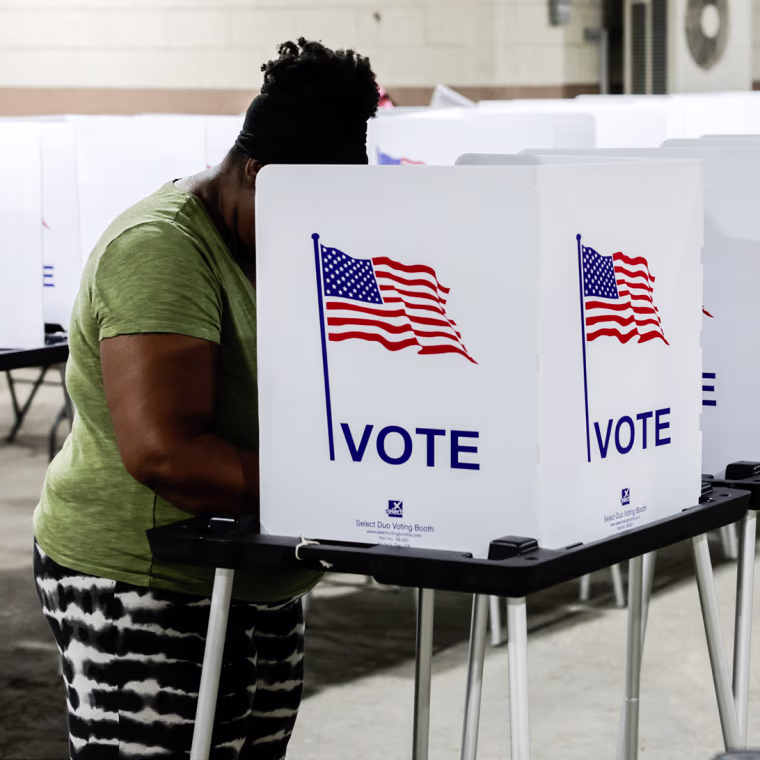 A person stands at a voting booth