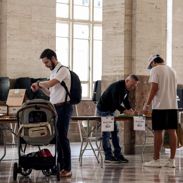 Poll workers help voters as they prepare to cast their ballots at a polling station in December 2025 in Miami, Fl.