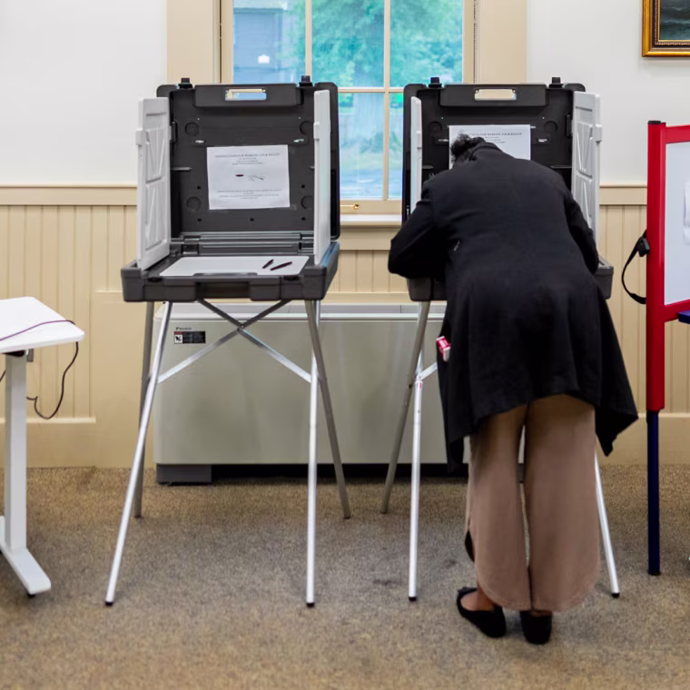 A voter casts their ballot at the Wenham Museum