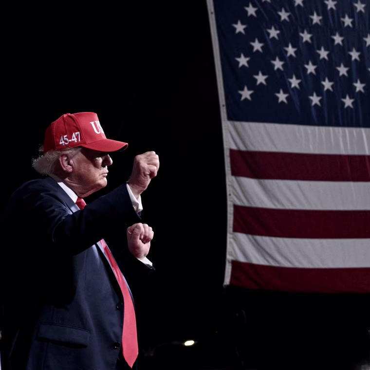 Donald Trump raises his fists while dancing on stage during an evening rally. 