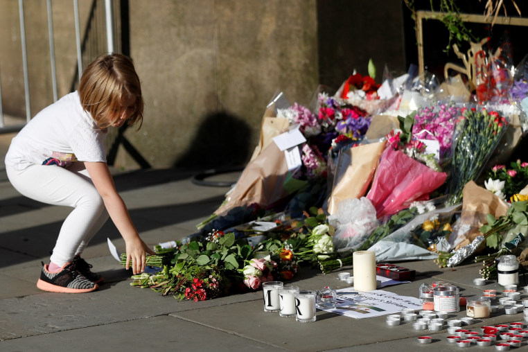 Image: A girl leaves flowers for the victims of an attack on concert goers at Manchester Arena, in central Manchester