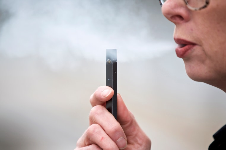 A woman exhales a puff of vapor from a Juul pen in Vancouver, Wash., on April 16, 2019.