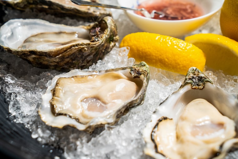Close-up of oysters in plate on table.