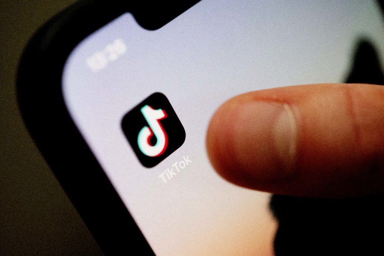 A teenager taps the TikTok app on a smartphone.