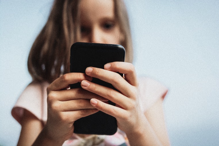 Close-up of girl using mobile phone outdoors