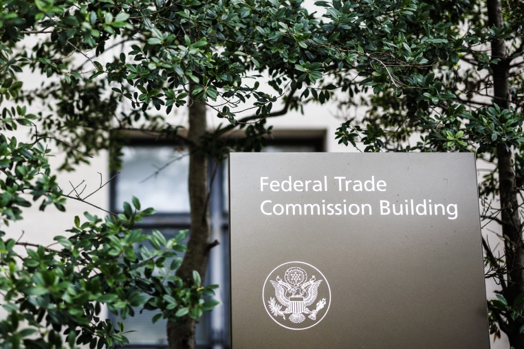 The Federal Trade Commission headquarters sign in the midst of tree branches and leaves